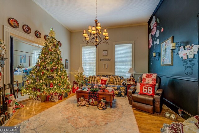 living room with light wood-type flooring, ornamental molding, and an inviting chandelier