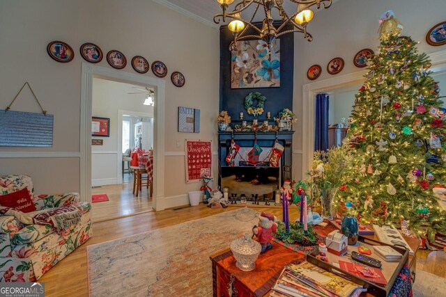 living room with hardwood / wood-style floors, ceiling fan with notable chandelier, and ornamental molding