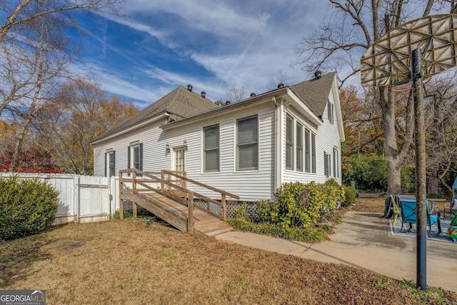 bungalow-style home with a patio area, a shingled roof, and fence