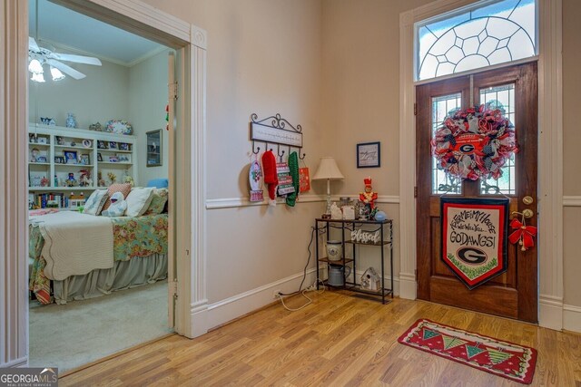 entrance foyer featuring wood-type flooring, ceiling fan, and ornamental molding