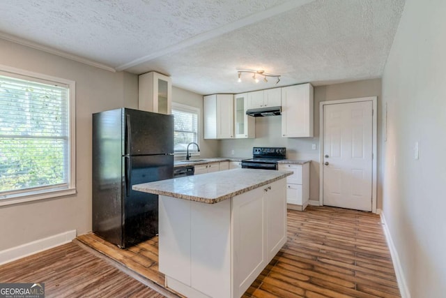 kitchen with hardwood / wood-style flooring, white cabinetry, a kitchen island, and black appliances