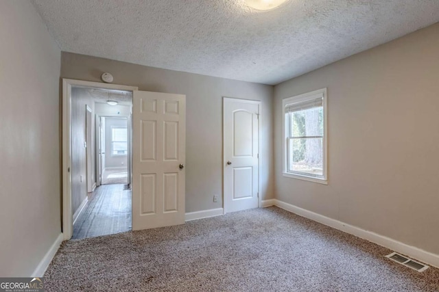 unfurnished bedroom featuring carpet and a textured ceiling