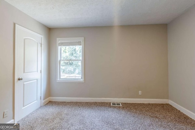 empty room with carpet floors and a textured ceiling