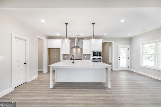 408 Bella Notte Cir Unit 26A, Warner Robins, GA 31088 - kitchen with stainless steel appliances, wall chimney exhaust hood, white cabinets, decorative backsplash, and light wood-type flooring