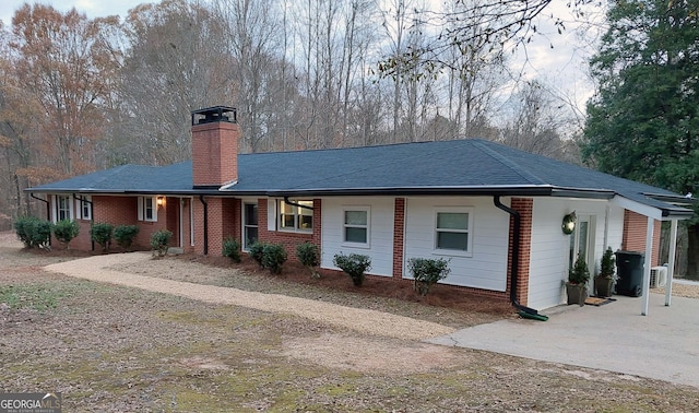 single story home featuring a chimney, brick siding, and driveway