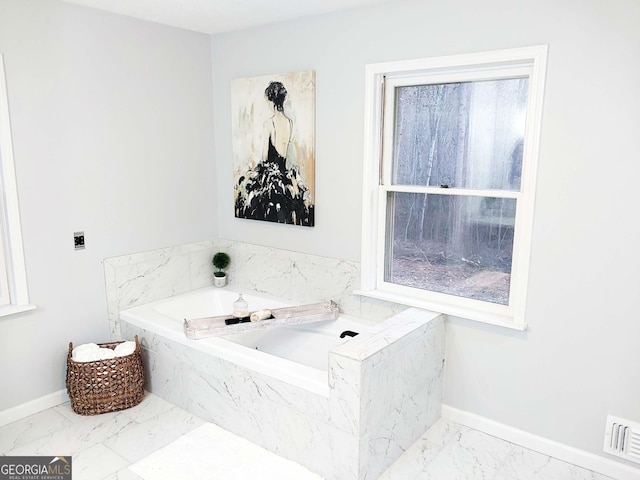 bathroom featuring a bath, visible vents, marble finish floor, and baseboards