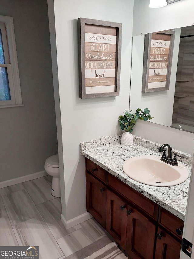 bathroom featuring vanity, toilet, and baseboards