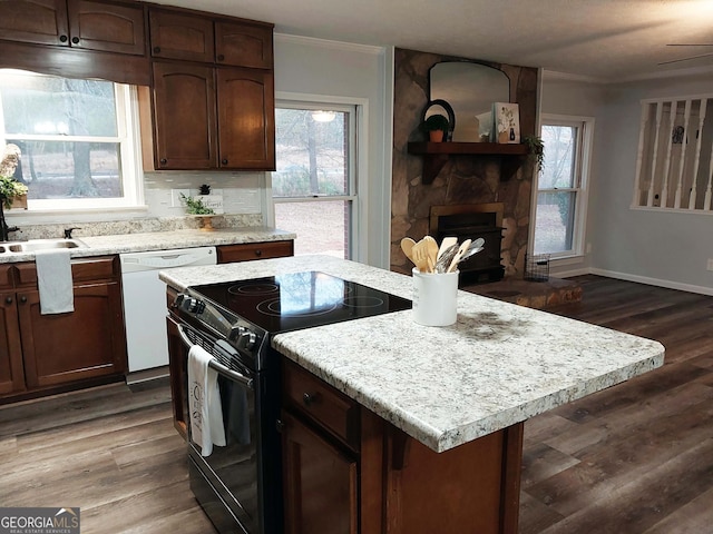 kitchen featuring black range with electric stovetop, dishwasher, dark wood-type flooring, and a stone fireplace