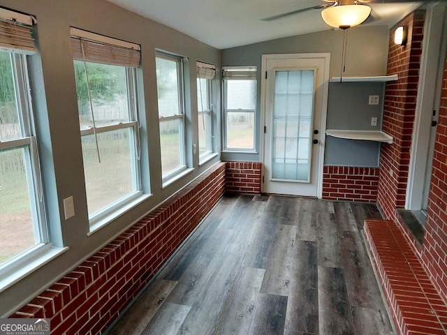 unfurnished sunroom featuring vaulted ceiling, wood finished floors, and a wealth of natural light