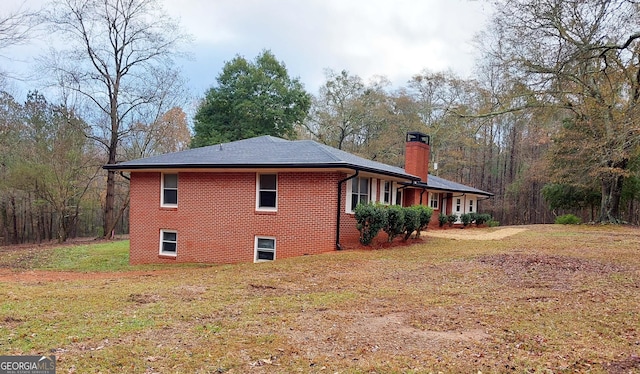 view of side of home featuring brick siding, a lawn, and a chimney