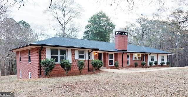 ranch-style house with a chimney, brick siding, and roof with shingles