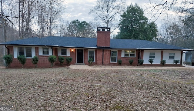 ranch-style house with a chimney and brick siding