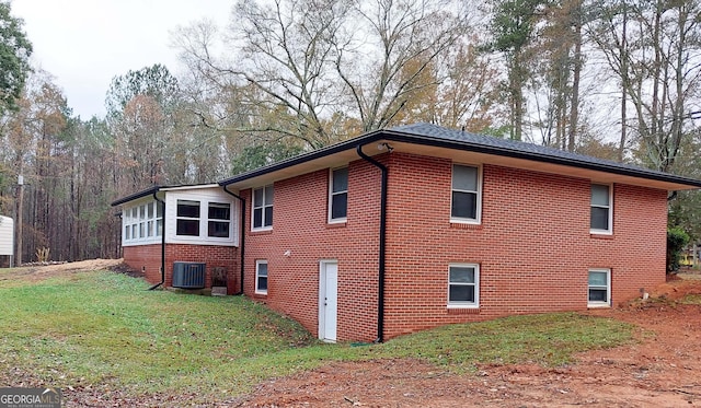 view of property exterior with a lawn, brick siding, and central AC