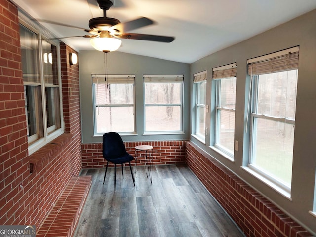 sunroom featuring brick wall, lofted ceiling, and wood finished floors
