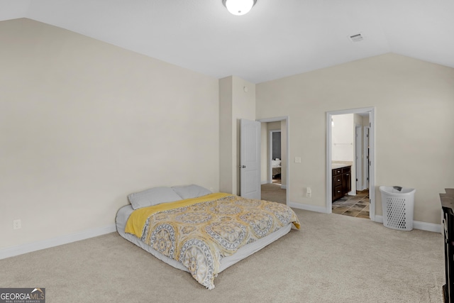 bedroom with light carpet, connected bathroom, and lofted ceiling