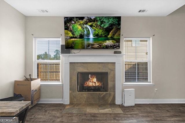 living room with dark hardwood / wood-style flooring and a tiled fireplace