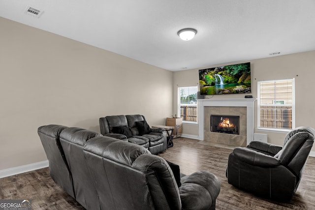 living room featuring a tiled fireplace and dark hardwood / wood-style floors