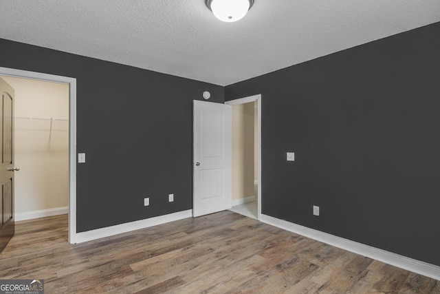 299 Archibald Ave SE, Ludowici, GA 31316 - unfurnished bedroom with baseboards, wood finished floors, a textured ceiling, and a walk in closet