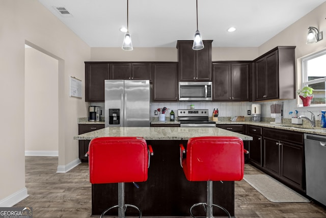 kitchen featuring sink, decorative light fixtures, a kitchen bar, a kitchen island, and appliances with stainless steel finishes