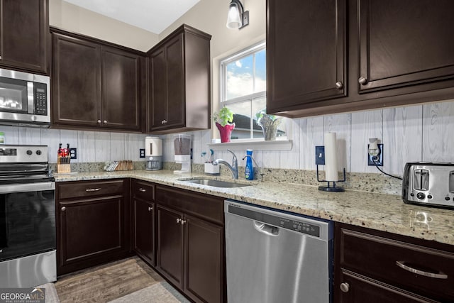 kitchen with sink, light hardwood / wood-style flooring, tasteful backsplash, light stone counters, and stainless steel appliances