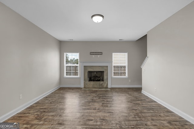 299 Archibald Ave SE, Ludowici, GA 31316 - unfurnished living room with baseboards, a tiled fireplace, and dark wood-type flooring