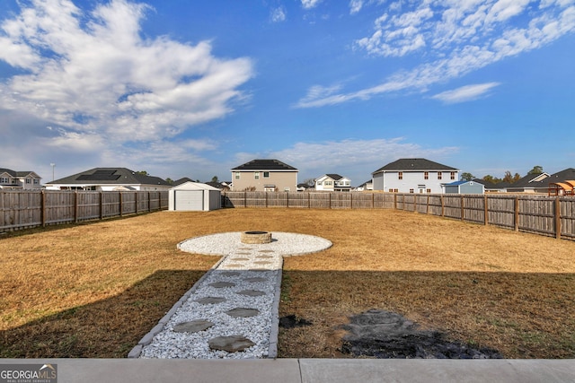 299 Archibald Ave SE, Ludowici, GA 31316 - view of yard featuring a fire pit, a residential view, a fenced backyard, and a shed