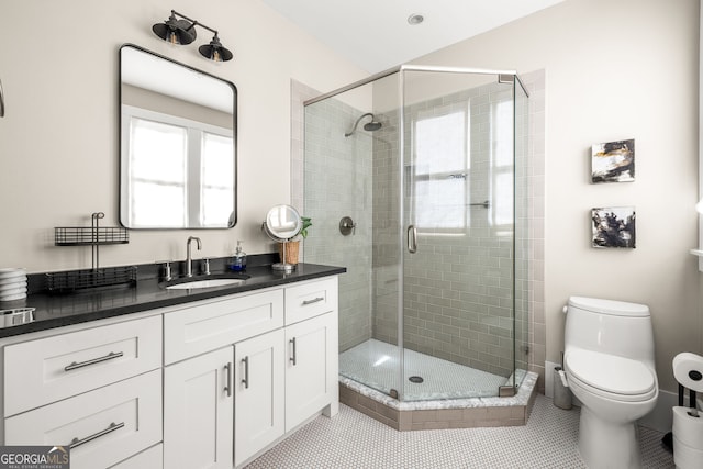 bathroom featuring tile patterned flooring, vanity, toilet, and a shower with shower door