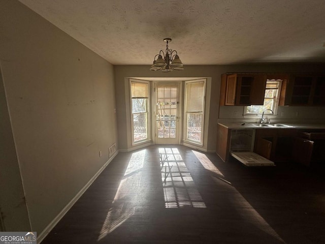 dining room featuring a wealth of natural light, sink, dark hardwood / wood-style floors, and a notable chandelier