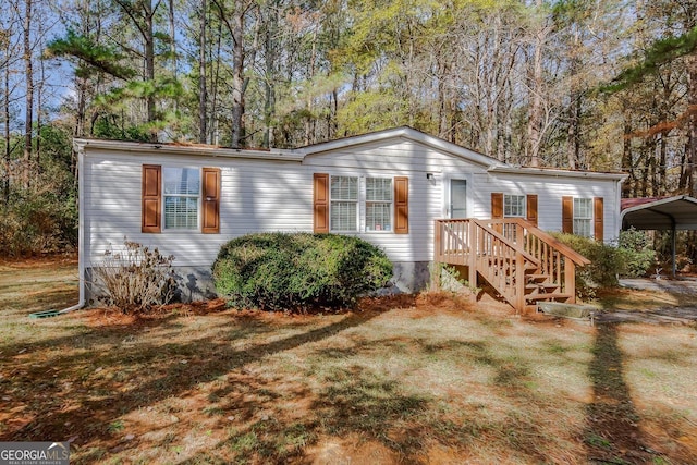 manufactured / mobile home with a front lawn and a carport