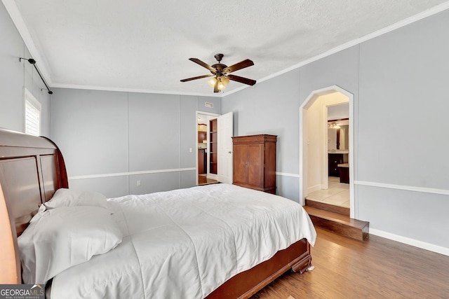 bedroom with hardwood / wood-style floors, ceiling fan, ornamental molding, and a textured ceiling