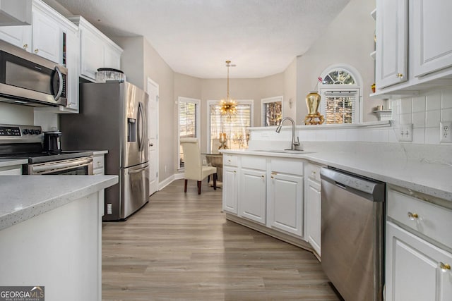 kitchen with white cabinets, pendant lighting, appliances with stainless steel finishes, and sink