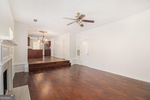 unfurnished living room featuring hardwood / wood-style flooring, a fireplace, visible vents, baseboards, and ceiling fan with notable chandelier