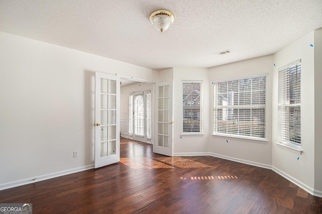 unfurnished room with hardwood / wood-style floors, french doors, visible vents, and baseboards