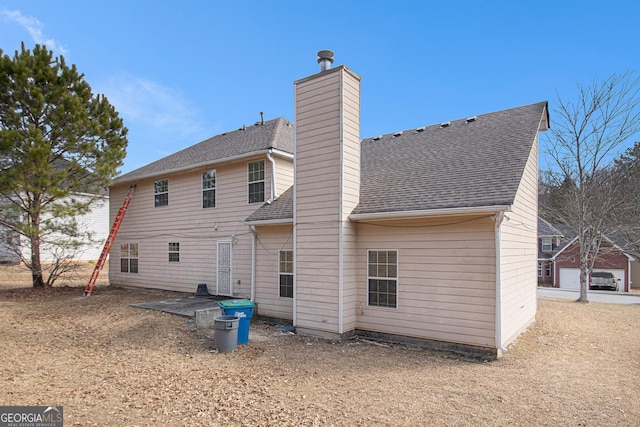 rear view of house featuring roof with shingles and a chimney