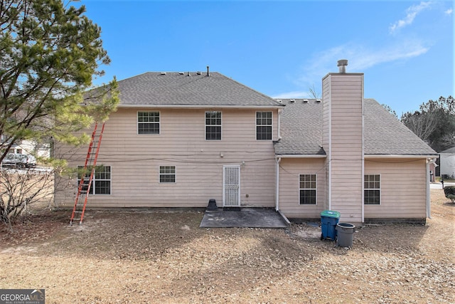 back of property featuring roof with shingles, a chimney, and a patio