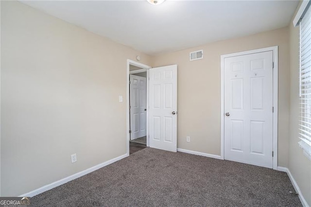 unfurnished bedroom featuring dark colored carpet and a closet