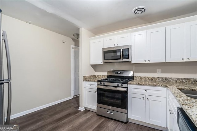 kitchen with light stone countertops, dark hardwood / wood-style flooring, stainless steel appliances, and white cabinetry