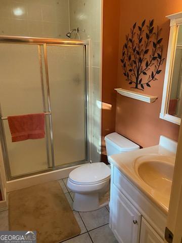 bathroom with vanity, an enclosed shower, tile patterned flooring, and toilet