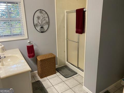 bathroom with an enclosed shower, vanity, and tile patterned floors