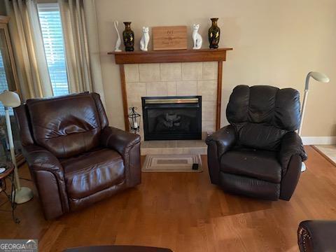 living area featuring wood-type flooring and a tiled fireplace