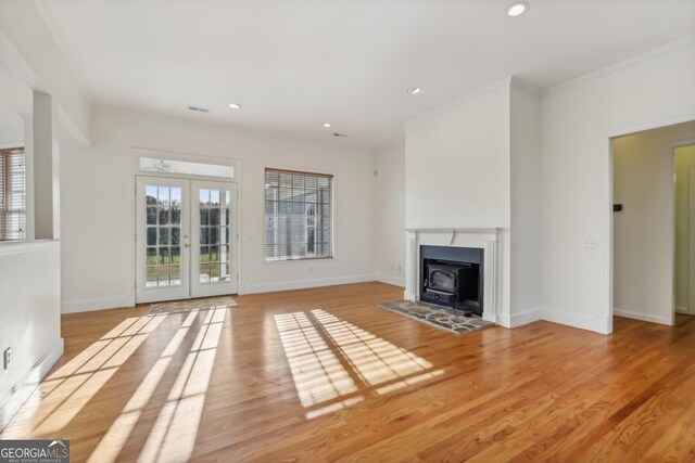 unfurnished living room with a wood stove, french doors, and light hardwood / wood-style flooring