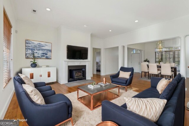 unfurnished living room with a wood stove, hardwood / wood-style floors, a healthy amount of sunlight, and ornamental molding