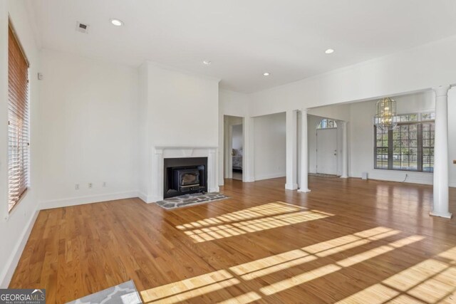 living room featuring a chandelier, light hardwood / wood-style floors, and decorative columns