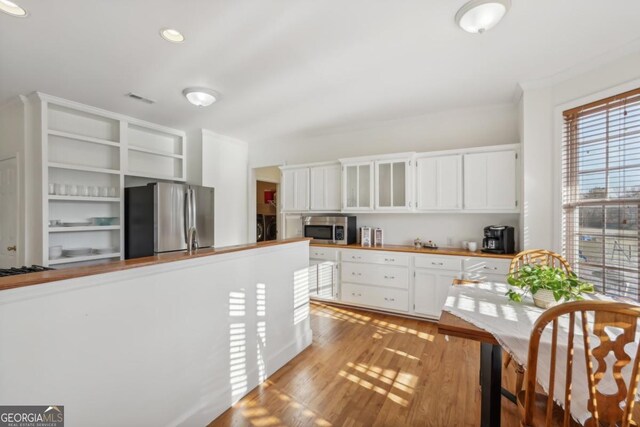 kitchen with appliances with stainless steel finishes, light stone counters, crown molding, sink, and light hardwood / wood-style flooring