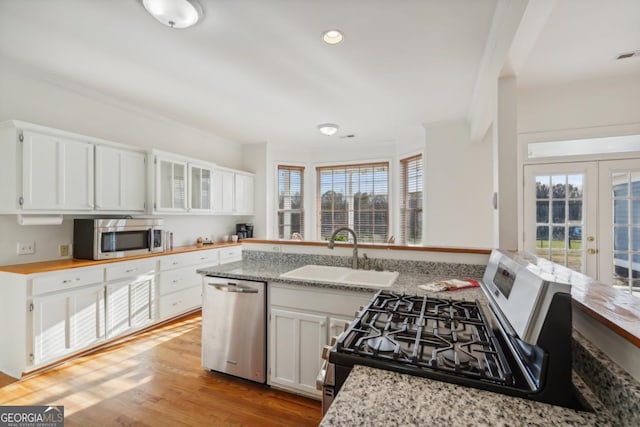 kitchen featuring french doors, stainless steel appliances, sink, white cabinets, and plenty of natural light