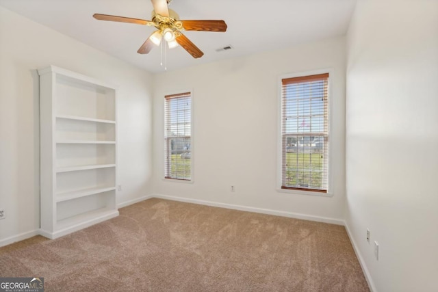 carpeted spare room featuring ceiling fan and a healthy amount of sunlight