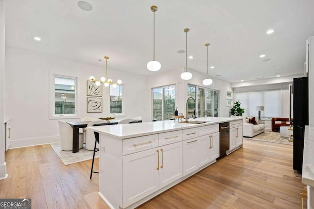 kitchen featuring sink, white cabinetry, a kitchen breakfast bar, pendant lighting, and a kitchen island with sink