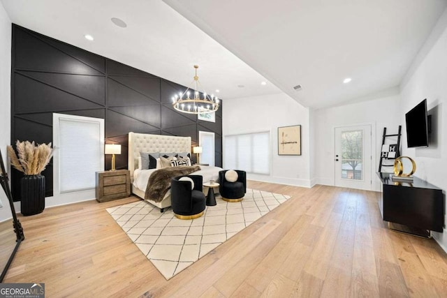 bedroom with a notable chandelier, access to outside, and light wood-type flooring