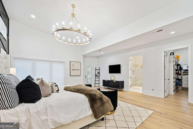 bedroom featuring a walk in closet, light wood-type flooring, a notable chandelier, and ensuite bath