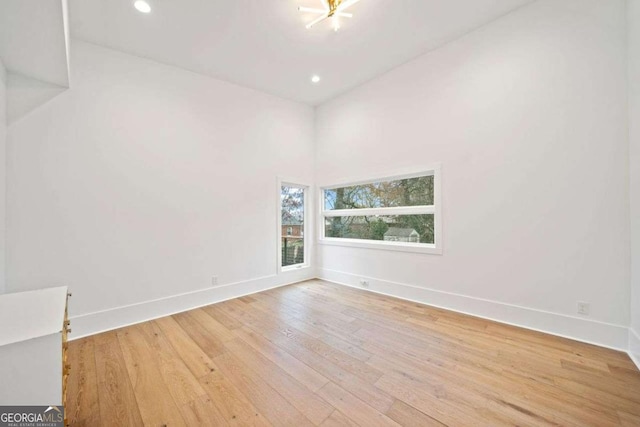 spare room with light hardwood / wood-style floors and a high ceiling